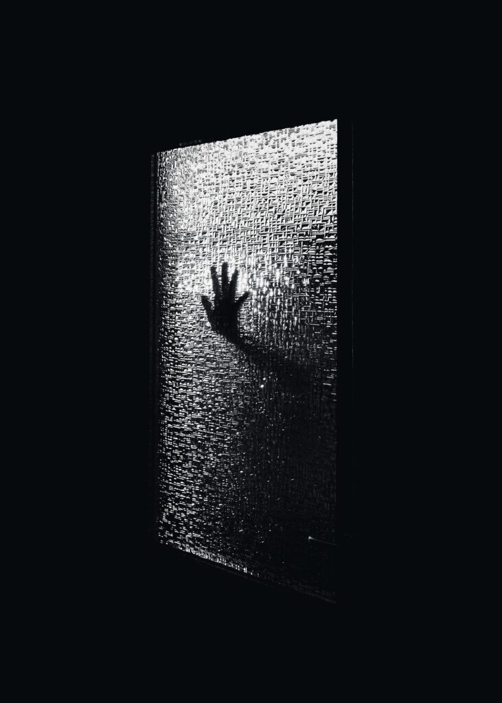 Image of a hand shadow behind a glass door for depression, anxiety and mental health